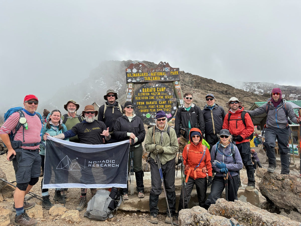 The crew at Uhuru Peak, Kilimanjaro, with the Nomadic Research flag