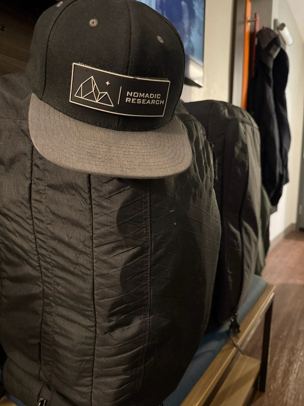 Alpine Hoodie hanging on a hook with NR hat